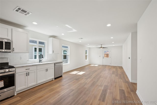 kitchen featuring visible vents, a sink, tasteful backsplash, white cabinetry, and appliances with stainless steel finishes