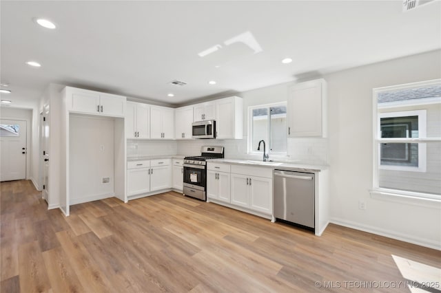 kitchen with visible vents, a sink, light countertops, light wood-style floors, and appliances with stainless steel finishes