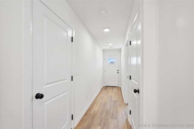 hall with light wood-style floors and baseboards