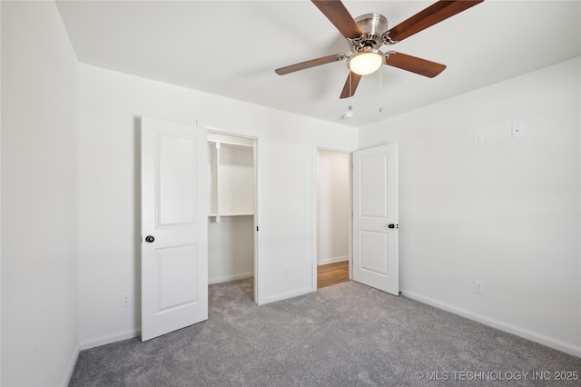 unfurnished bedroom with a spacious closet, carpet, and baseboards