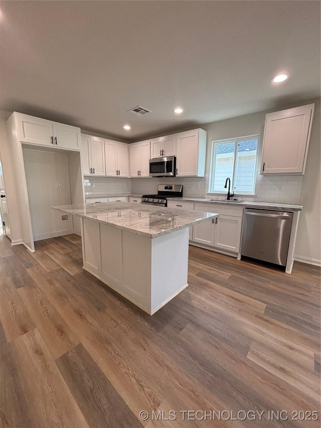 kitchen featuring stainless steel appliances, visible vents, wood finished floors, and white cabinetry