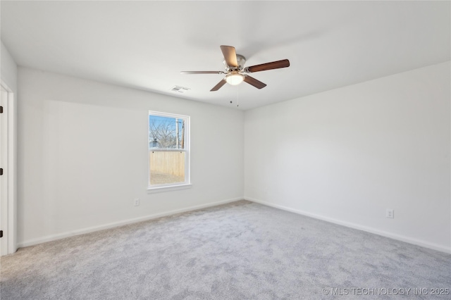 carpeted spare room with visible vents, baseboards, and ceiling fan