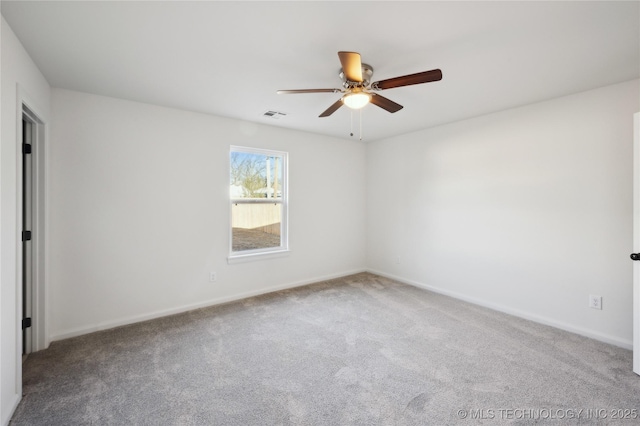 carpeted spare room featuring a ceiling fan, visible vents, and baseboards