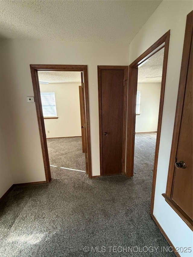 corridor with baseboards, a textured ceiling, and carpet