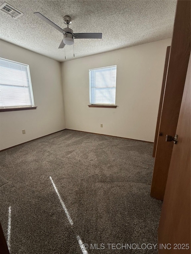 spare room with carpet, a ceiling fan, visible vents, and a textured ceiling