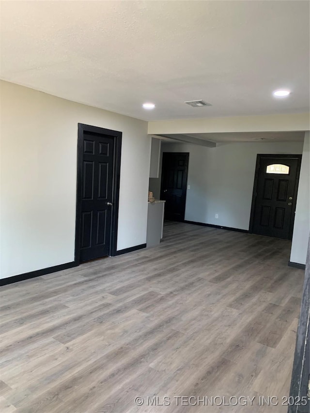 empty room with light wood-style floors, baseboards, visible vents, and a textured ceiling