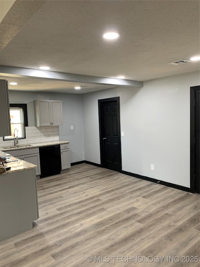 kitchen with light wood-style flooring, a sink, light countertops, black dishwasher, and tasteful backsplash