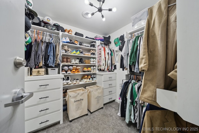 walk in closet featuring carpet floors and a chandelier