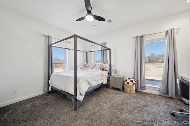 carpeted bedroom with visible vents, multiple windows, baseboards, and ceiling fan