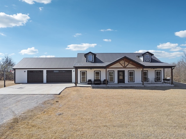 modern farmhouse with concrete driveway, an attached garage, covered porch, and metal roof