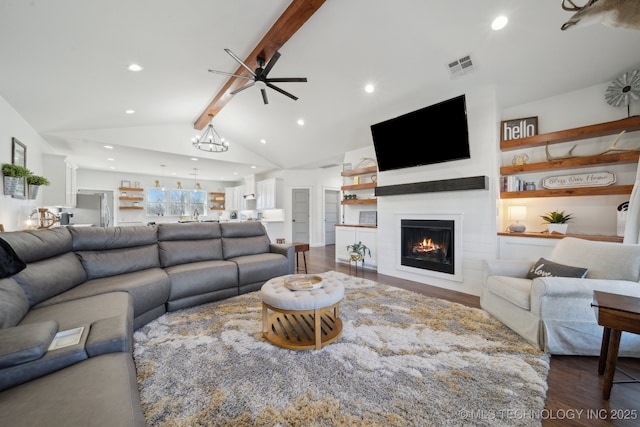 living room with visible vents, vaulted ceiling with beams, dark wood-type flooring, ceiling fan, and a lit fireplace