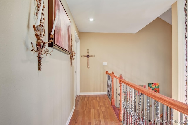 corridor featuring baseboards, light wood-style floors, and an upstairs landing