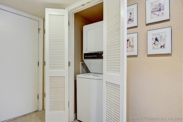 laundry area with light tile patterned flooring, stacked washer / dryer, and laundry area