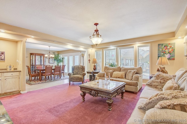 living room with an inviting chandelier, carpet floors, and a textured ceiling