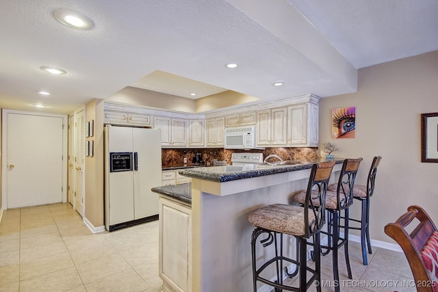 kitchen featuring white appliances, a breakfast bar area, a peninsula, light tile patterned flooring, and decorative backsplash