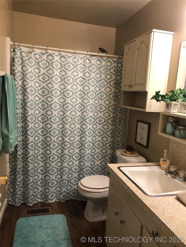 full bath with visible vents, toilet, wood finished floors, and vanity