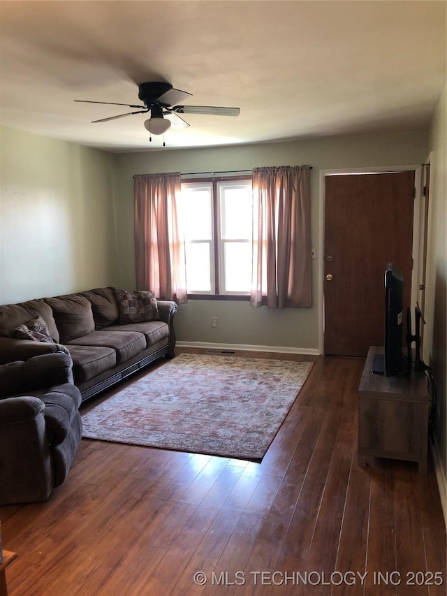 living area with baseboards, ceiling fan, and wood-type flooring