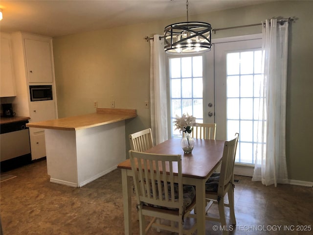 dining space with baseboards, a healthy amount of sunlight, and an inviting chandelier