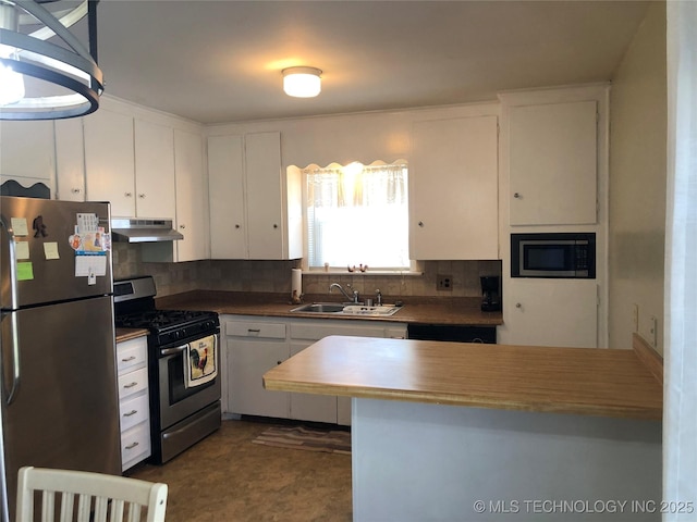 kitchen featuring a sink, under cabinet range hood, white cabinetry, stainless steel appliances, and decorative backsplash