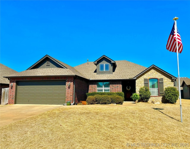 view of front of house with a front yard, driveway, roof with shingles, a garage, and brick siding