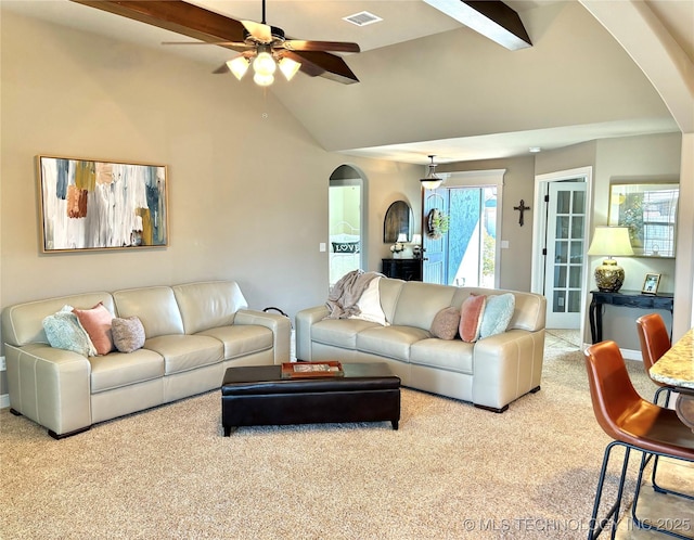 living room with visible vents, ceiling fan, lofted ceiling with beams, carpet floors, and arched walkways