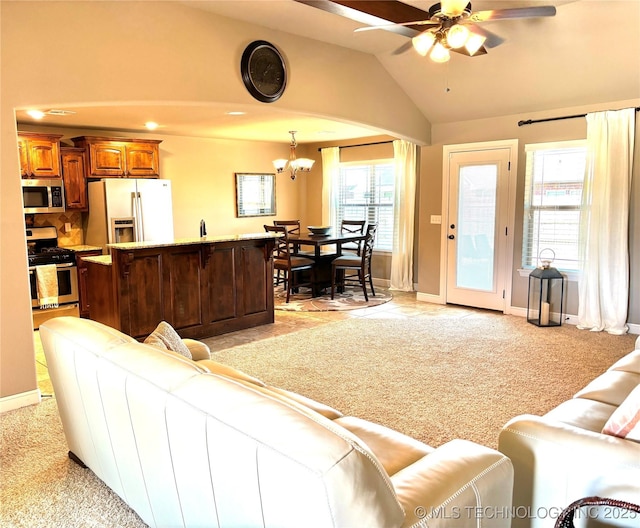 living room featuring baseboards, ceiling fan with notable chandelier, light carpet, and vaulted ceiling