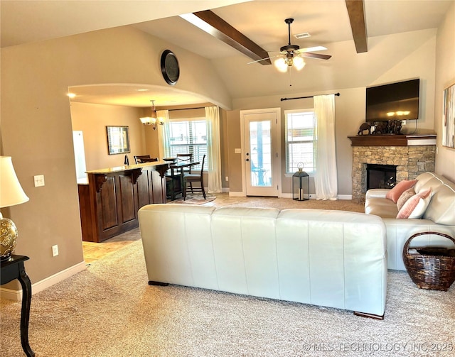 living area with visible vents, ceiling fan with notable chandelier, a stone fireplace, light colored carpet, and vaulted ceiling with beams