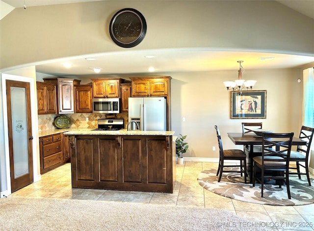 kitchen with a notable chandelier, light stone counters, tasteful backsplash, stainless steel appliances, and lofted ceiling