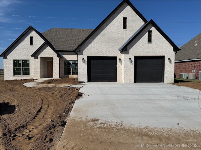 view of front of property with concrete driveway, central air condition unit, brick siding, and a garage