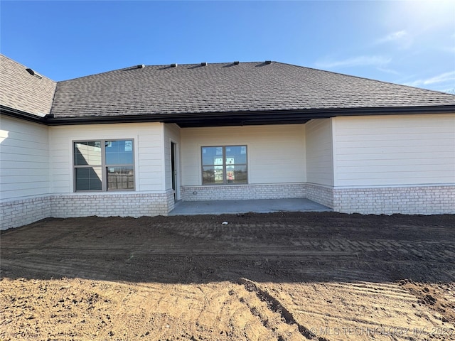 back of house with a patio area, brick siding, and a shingled roof