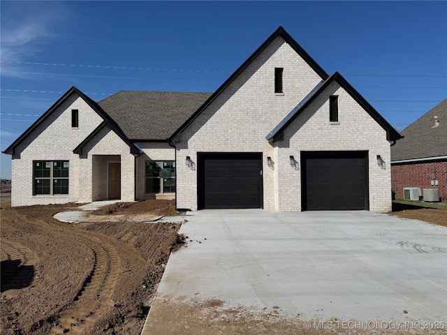 view of front of property featuring concrete driveway, a garage, brick siding, and central AC