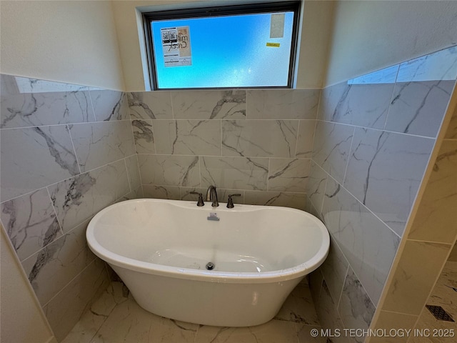 full bathroom featuring tile walls, a soaking tub, and marble finish floor