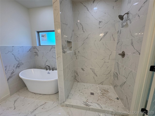 bathroom featuring a soaking tub, marble finish floor, and a tile shower