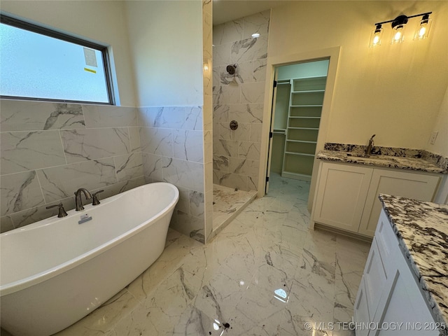 bathroom featuring a freestanding bath, marble finish floor, vanity, and a walk in shower