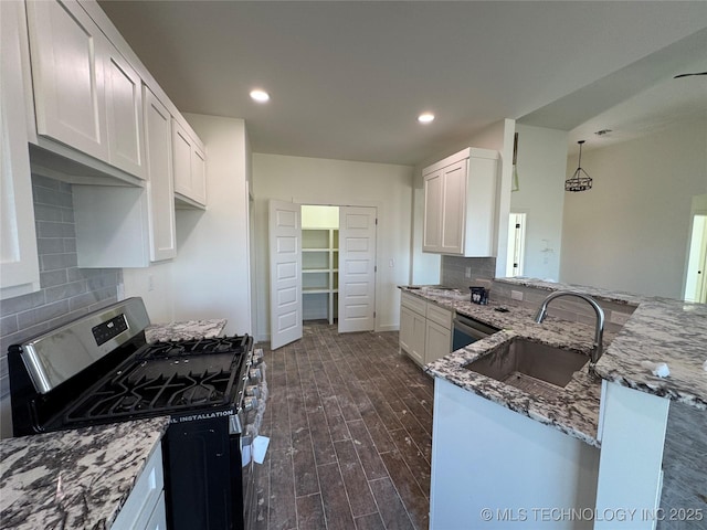 kitchen with stainless steel gas range oven, a sink, dishwasher, light stone counters, and dark wood-style flooring