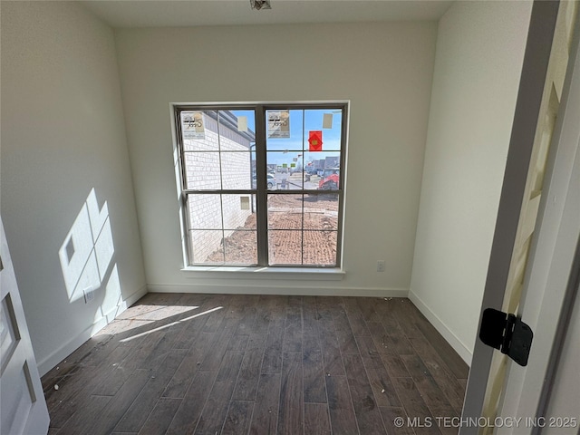 spare room with dark wood-type flooring and baseboards