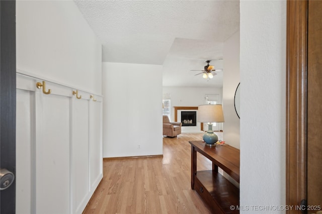 hallway featuring light wood-type flooring and a textured ceiling