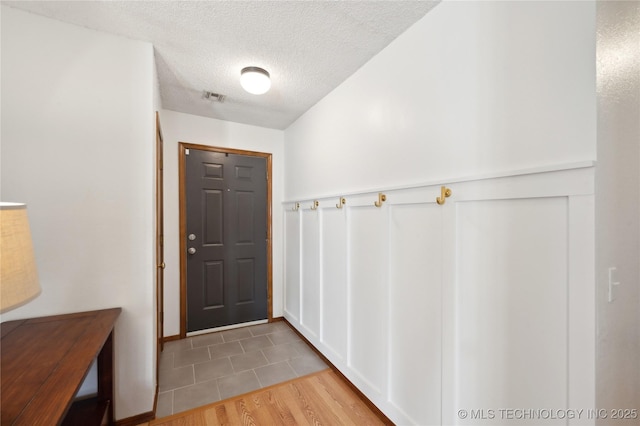 entrance foyer featuring visible vents, a textured ceiling, and wood finished floors