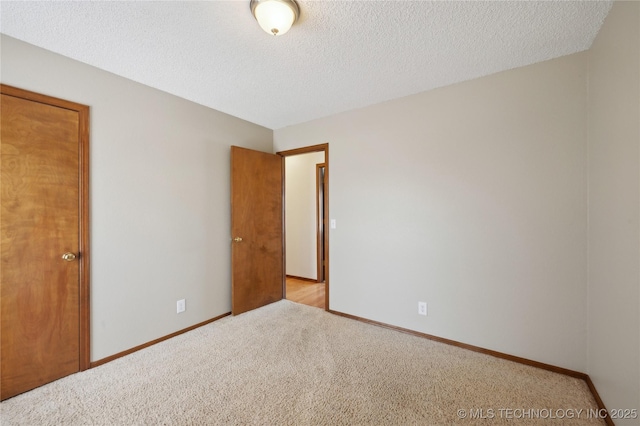 carpeted empty room with baseboards and a textured ceiling