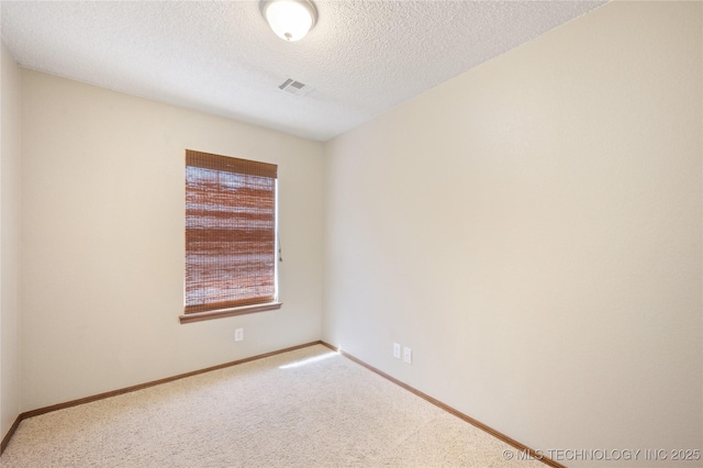 empty room with carpet, baseboards, and a textured ceiling