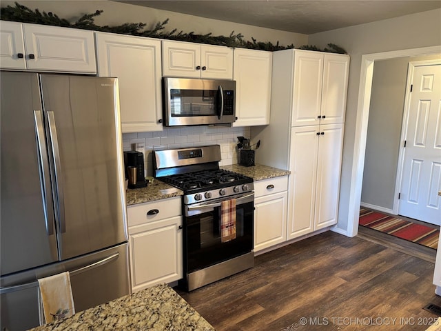 kitchen featuring light stone countertops, dark wood-style flooring, white cabinets, appliances with stainless steel finishes, and backsplash