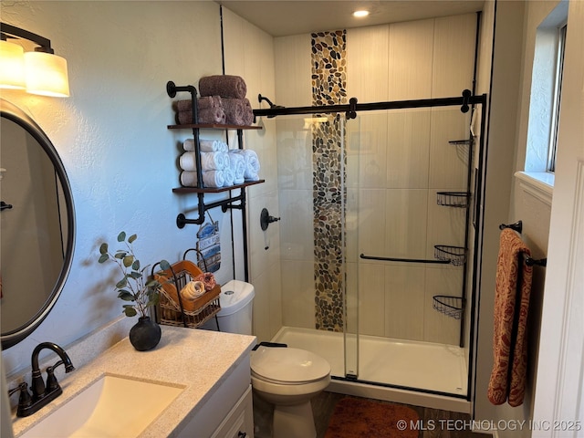 bathroom with a stall shower, toilet, and vanity