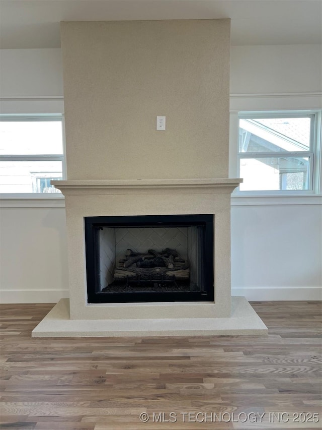 details with a fireplace with raised hearth, baseboards, and wood finished floors