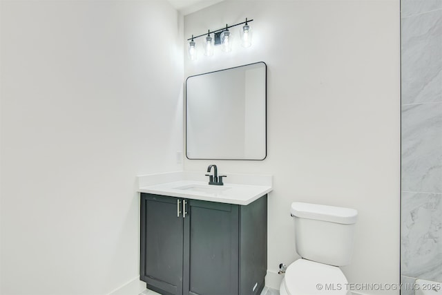 bathroom with toilet, vanity, and baseboards