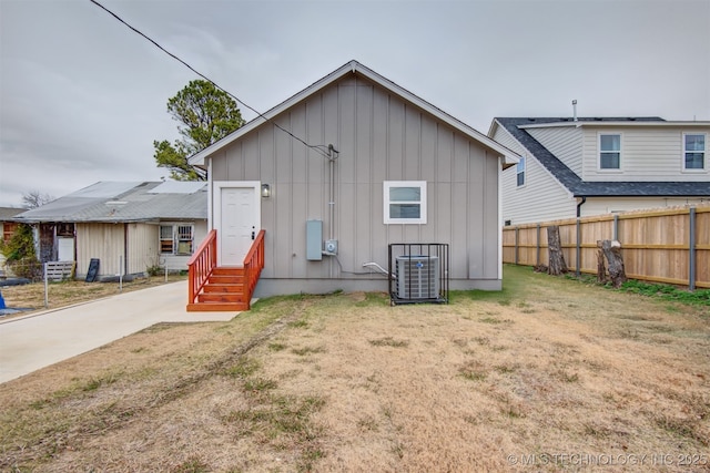 rear view of house featuring a yard, fence, board and batten siding, and entry steps