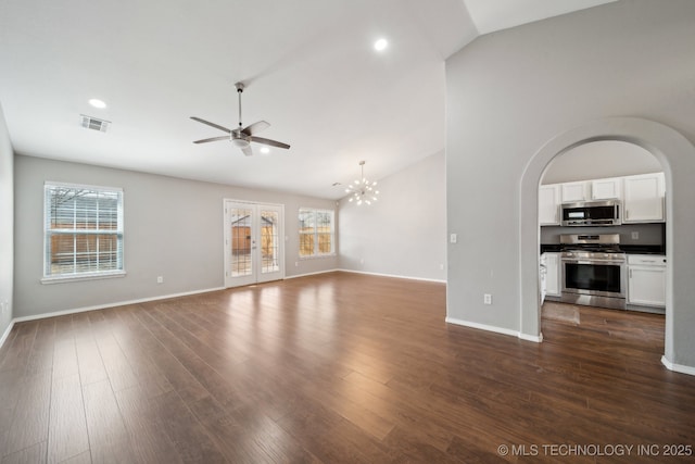 unfurnished living room featuring dark wood finished floors, plenty of natural light, ceiling fan with notable chandelier, and visible vents