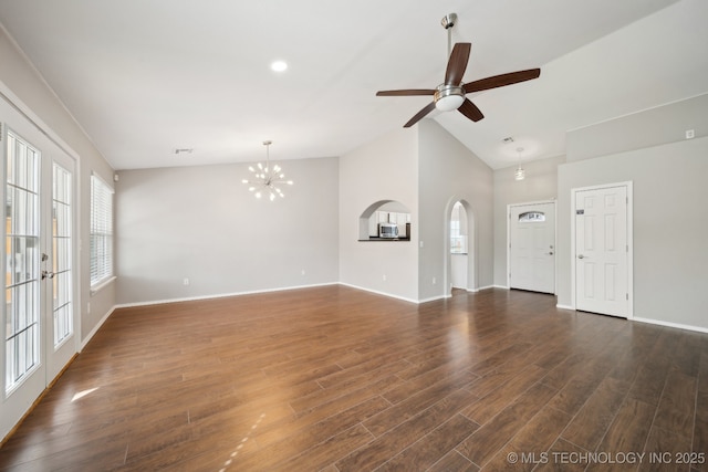 unfurnished living room featuring dark wood-type flooring, baseboards, ceiling fan with notable chandelier, arched walkways, and high vaulted ceiling