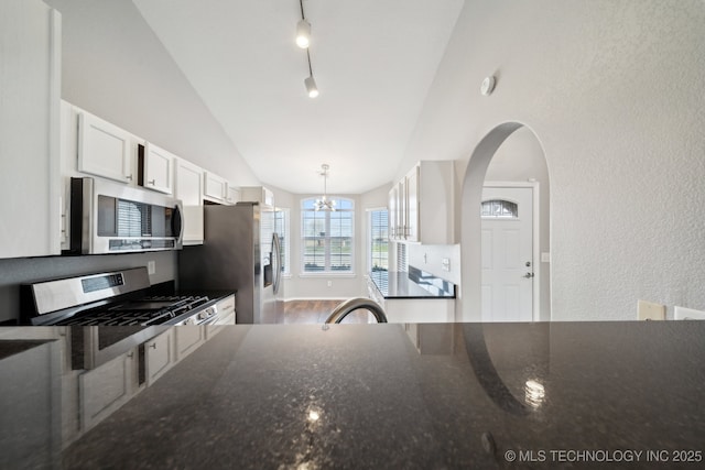 kitchen featuring vaulted ceiling, white cabinets, dark stone countertops, and appliances with stainless steel finishes