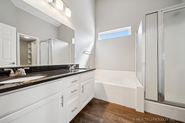 full bath featuring a garden tub, wood finished floors, a stall shower, and a sink