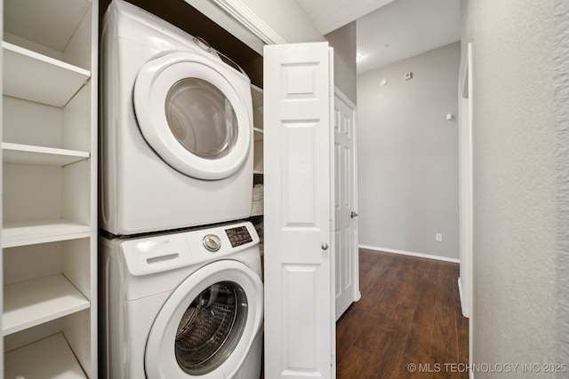 clothes washing area with laundry area, stacked washer and dryer, wood finished floors, and baseboards